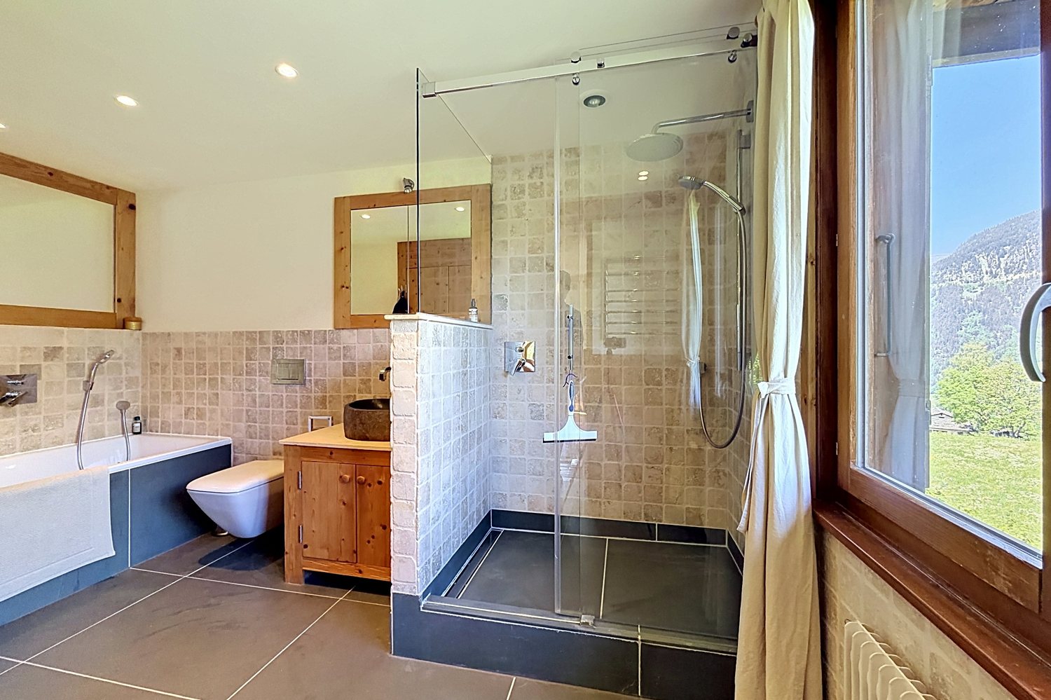 La salle de bains principale rénovée : douche à l'italienne et baignoire.